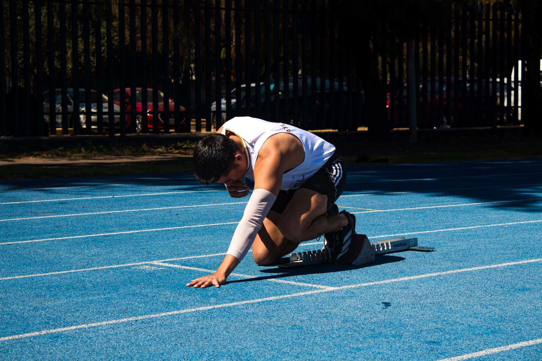 Jugendlicher Sprinter im Startblock auf blauer Laufbahn