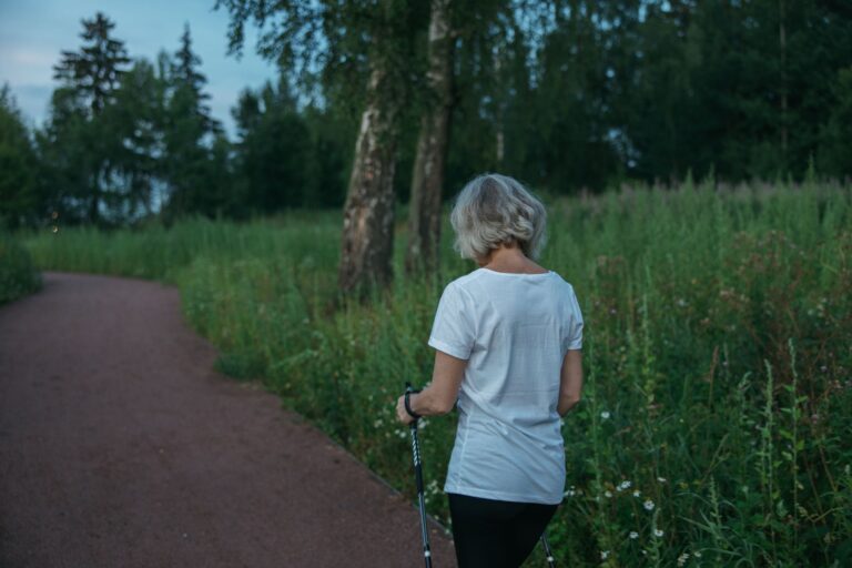 Frau beim Nordic Walking auf einem Parkweg am Abend