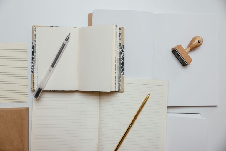 Leere Notizbücher, Stifte und ein Stempel auf einem Schreibtisch