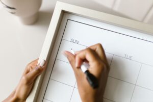 Hand trägt Termine in einen Wandkalender ein