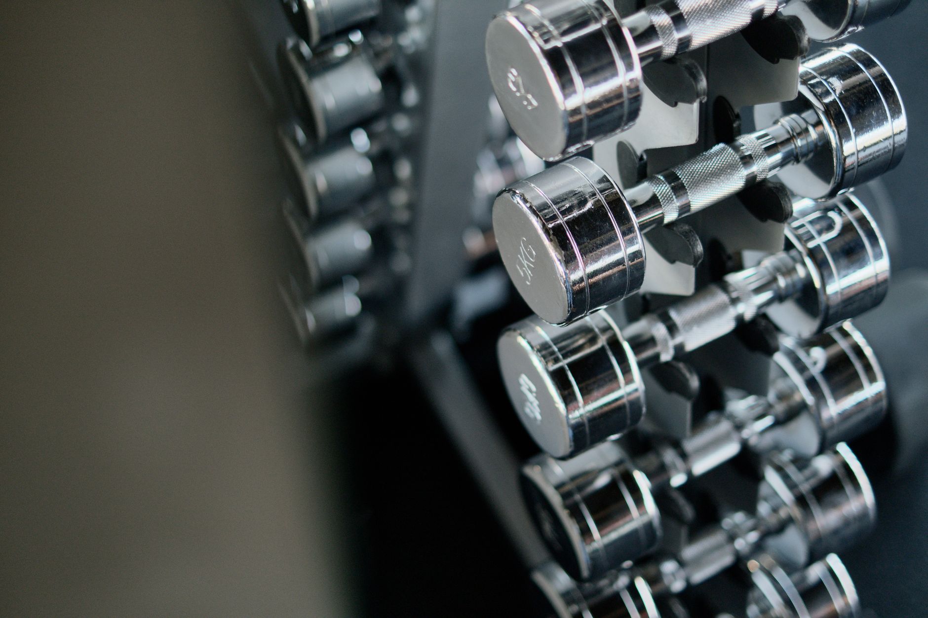 Chromfarbene Kurzhanteln in einem Hantelständer im Fitnessstudio